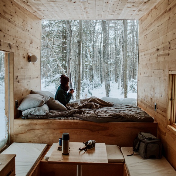 Girl sits in bed of a tiny house that is clear and has been decluttered.